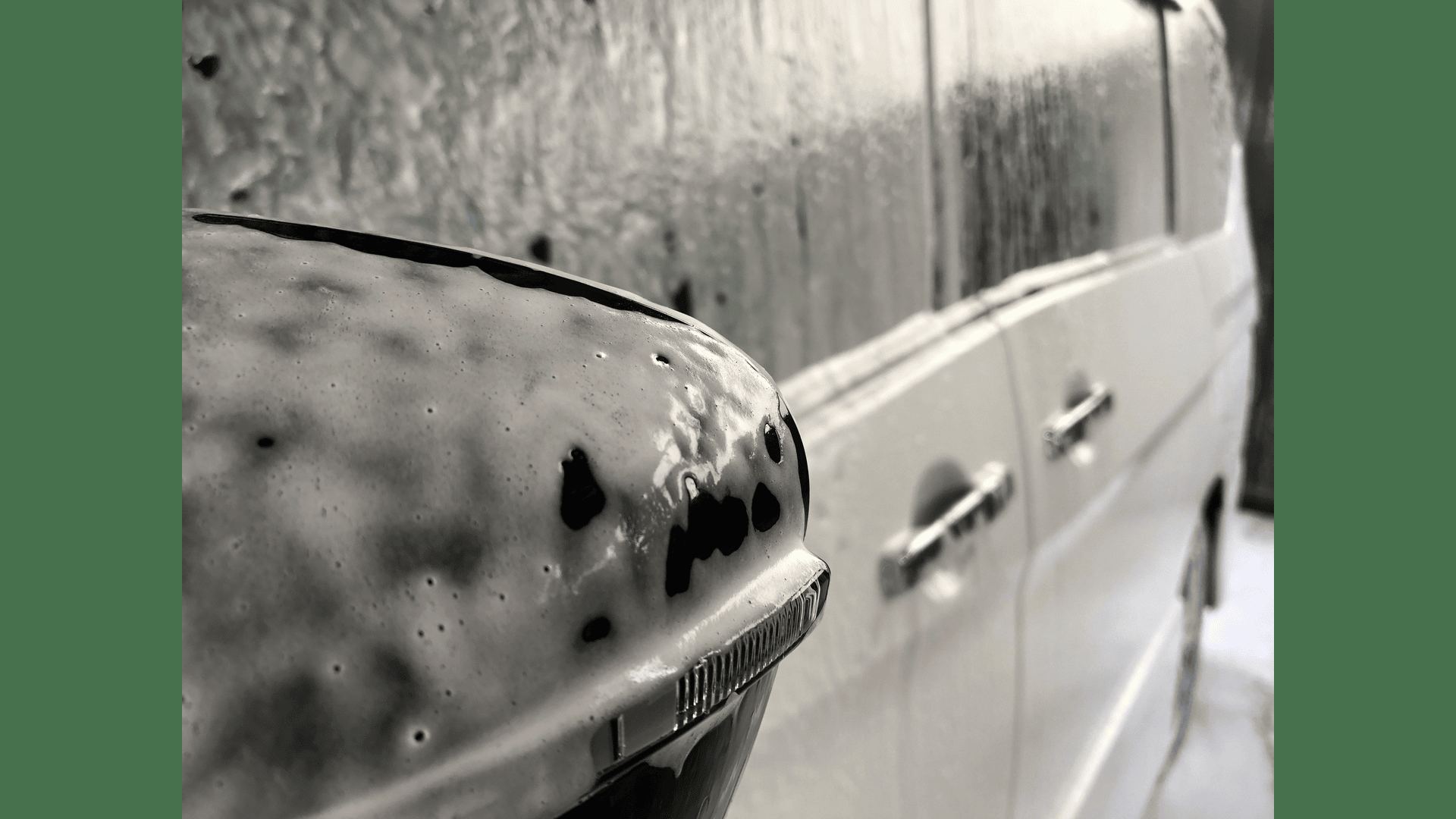 A car covered in soap suds inside a wash bay